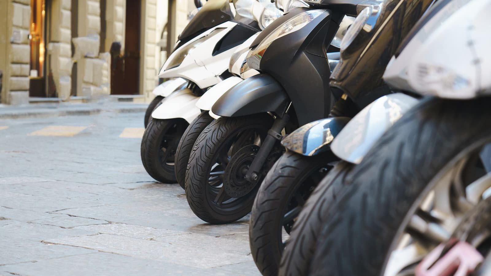 A close-up of the wheels of electric scooters parked in a row on a city street